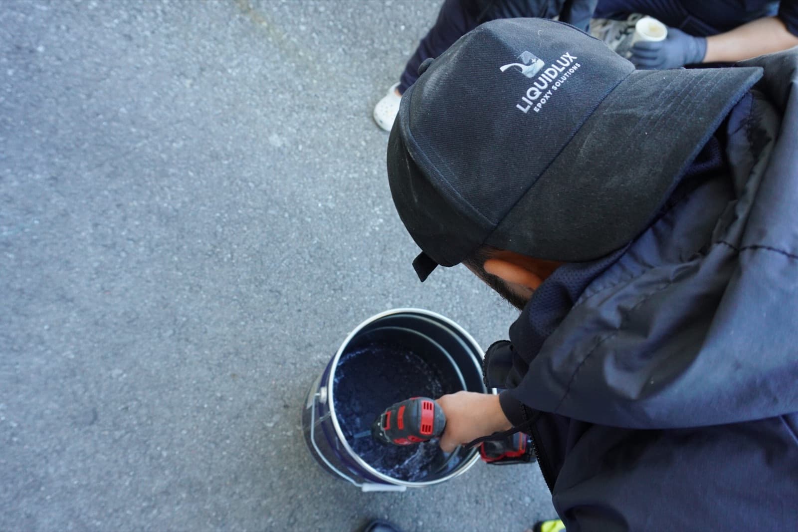 A LiquidLux installer power-mixing pigmented epoxy resin on site